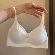 Women's white wireless sports bra with gathered cups, scalloped neckline, thin straps, and front bow accents