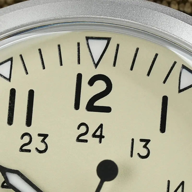 Militado ML07 quartz military watch dial close-up with beige face, 24-hour markings, black numerals, and silver bezel.