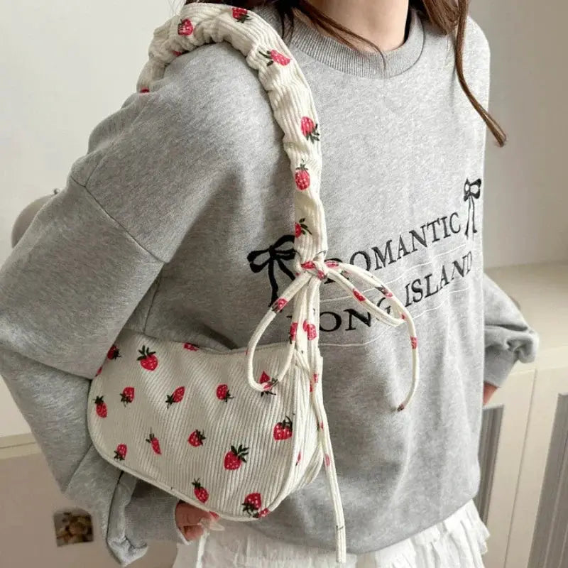 Cream corduroy underarm bag by Simples Market with strawberry print, half-moon shape and braided strap.