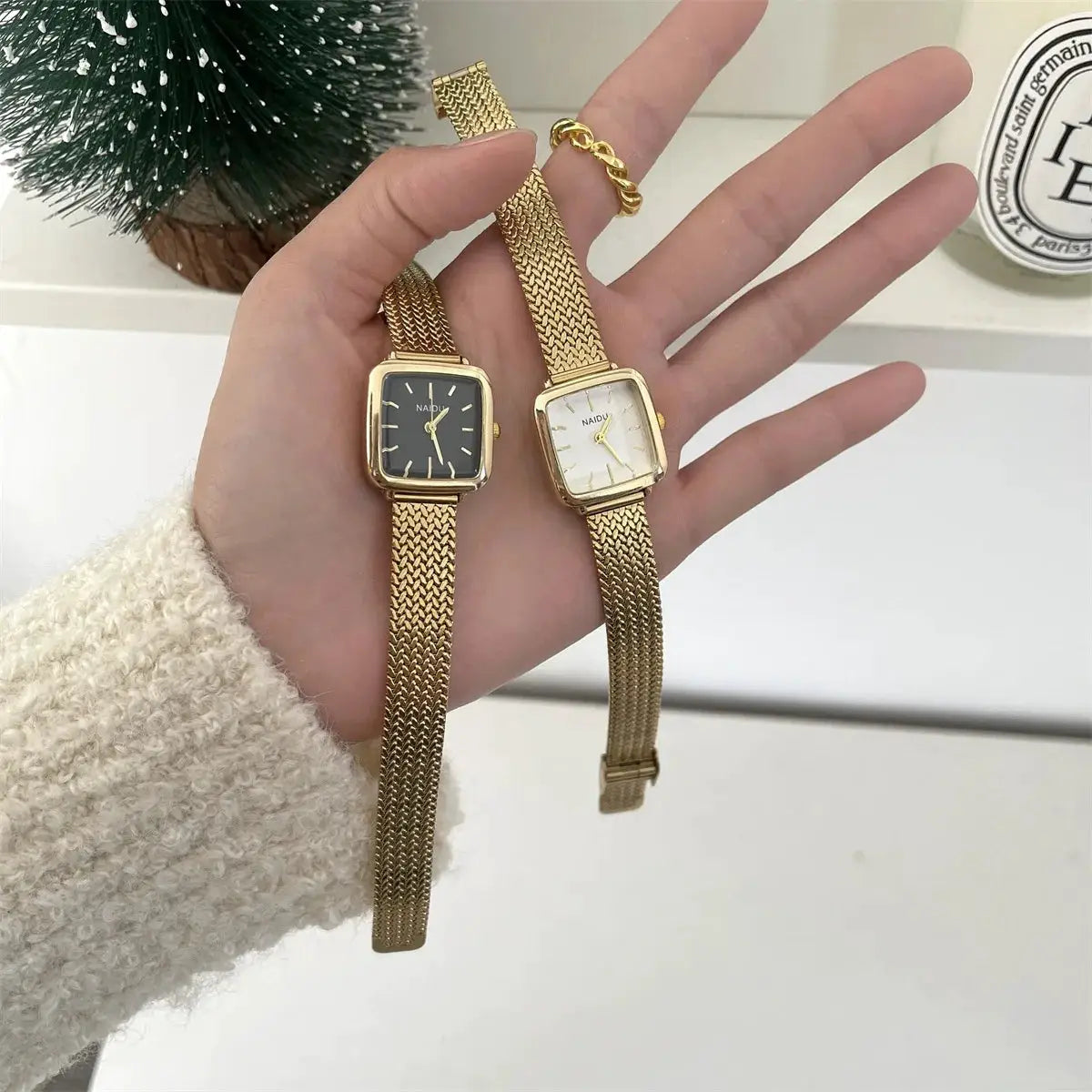 Two gold-tone NAIDU women's quartz wristwatches with square dials and mesh stainless steel bands.