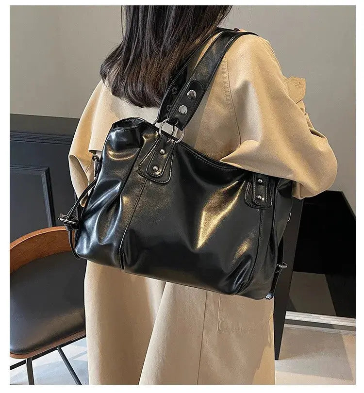 Shoulder bag in black PU leather with soft interior compartments, dual top handles and shoulder strap