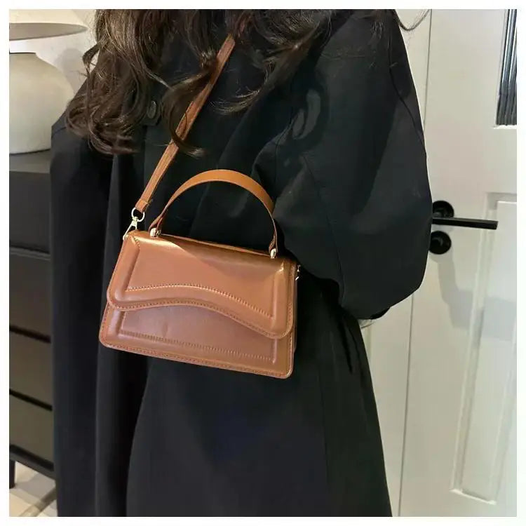 PU leather handbag in tan brown with top handle and crossbody strap