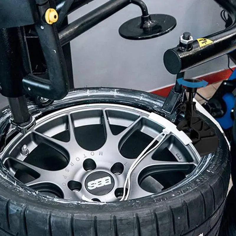 Bead clamp tire changer tool for universal car wheels; black plastic clamp mounted on a silver alloy rim.