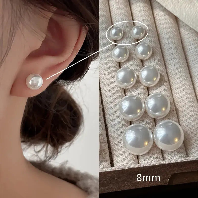 Pearl stud earrings, 8mm white pearls, worn on a woman's ear