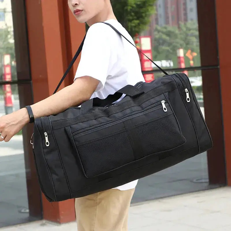 Duffel gym bag in black with multiple zip pockets and a mesh side pocket, carried by a person.