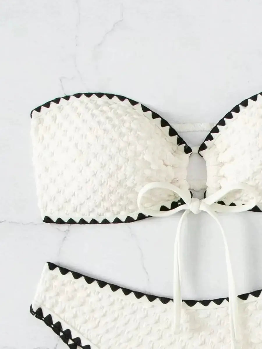 Simples Market white two-piece strapless bikini with lace-textured fabric, black zigzag trim and bow
