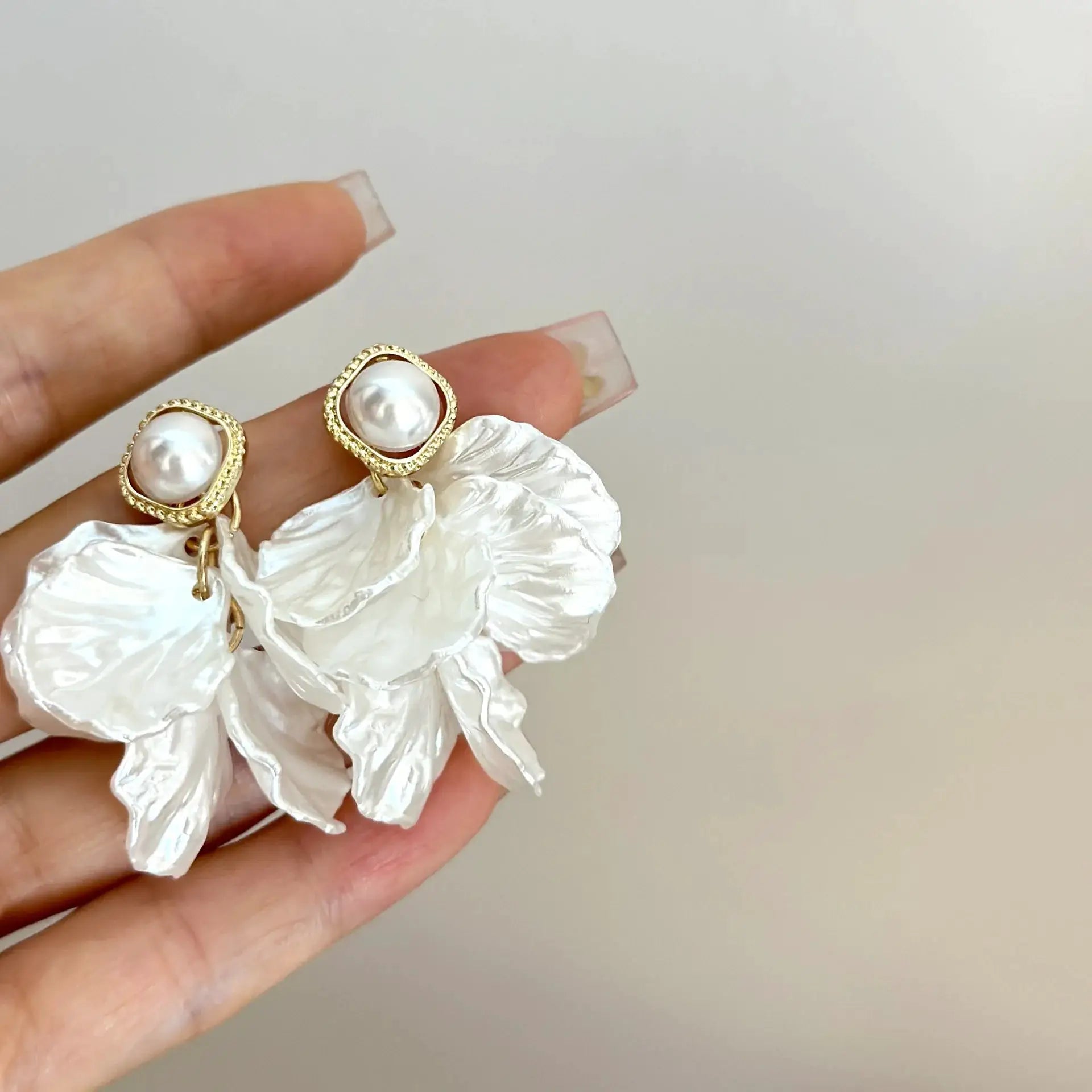 Pair of gold-tone shell flower pendant earrings with white pearl centers and beaded border
