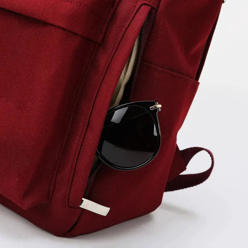 Red canvas backpack with sunglasses tucked in side pocket