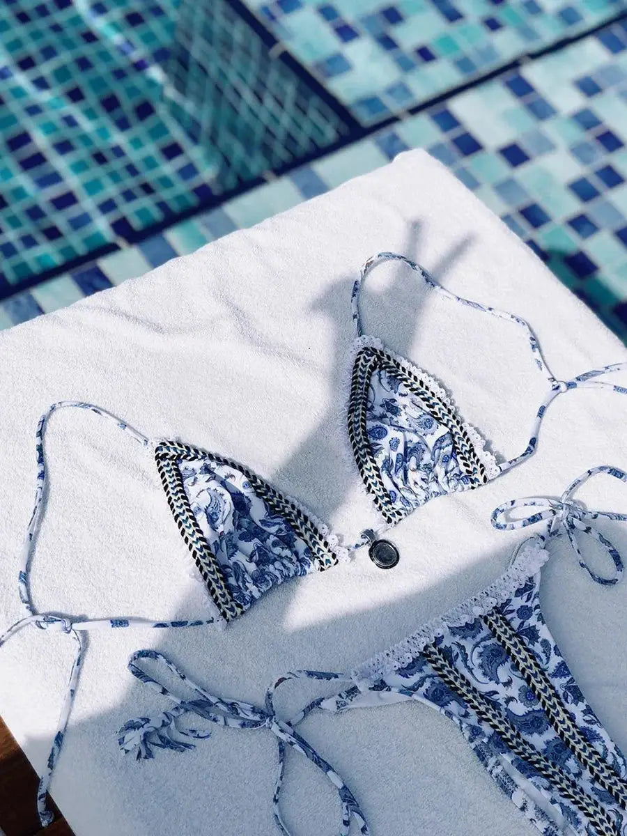 Bikini set by Simples Market, blue and white patterned two-piece with triangle top and thong bottom, poolside.