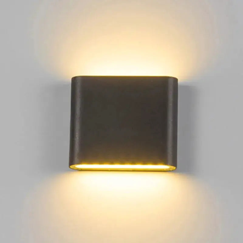 Simples Market square LED wall lamp, dark aluminum outdoor wall light with warm yellow glow.