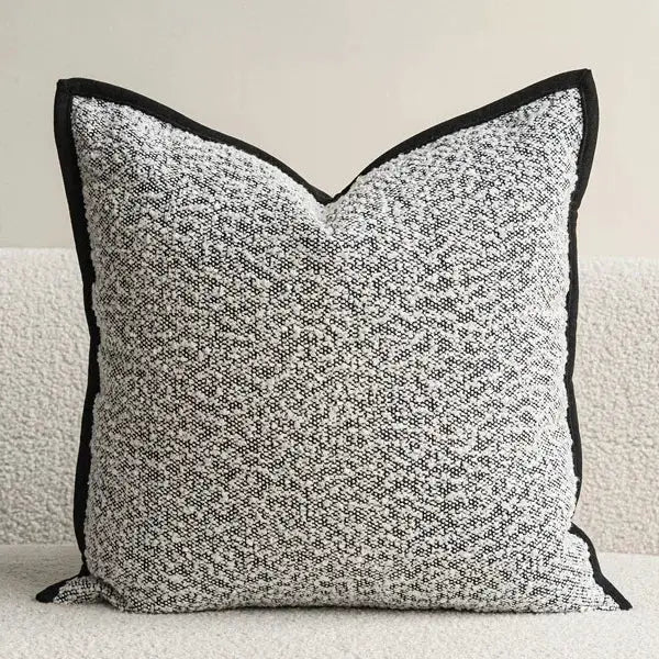 Decorative pillow cover with ivory and black speckled pattern and black piping trim