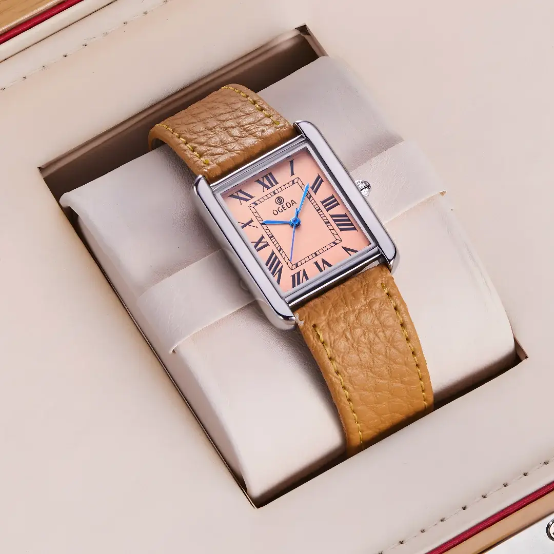 OGEDA square-dial wristwatch with tan leather strap, peach dial, blue hands, stainless steel case