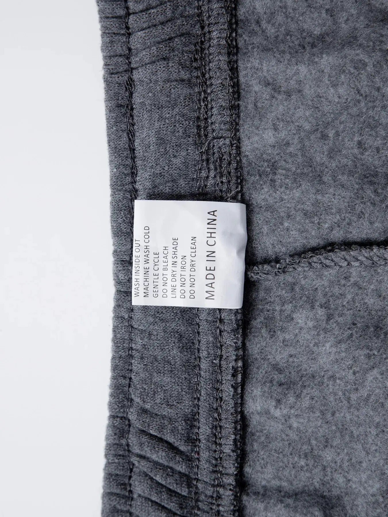 Men's grey joggers fabric close-up with care label reading made in China