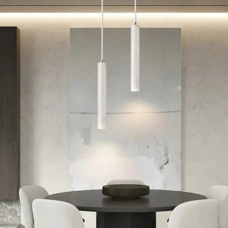 Pair of white cylindrical LED pendant lamps over a round dining table