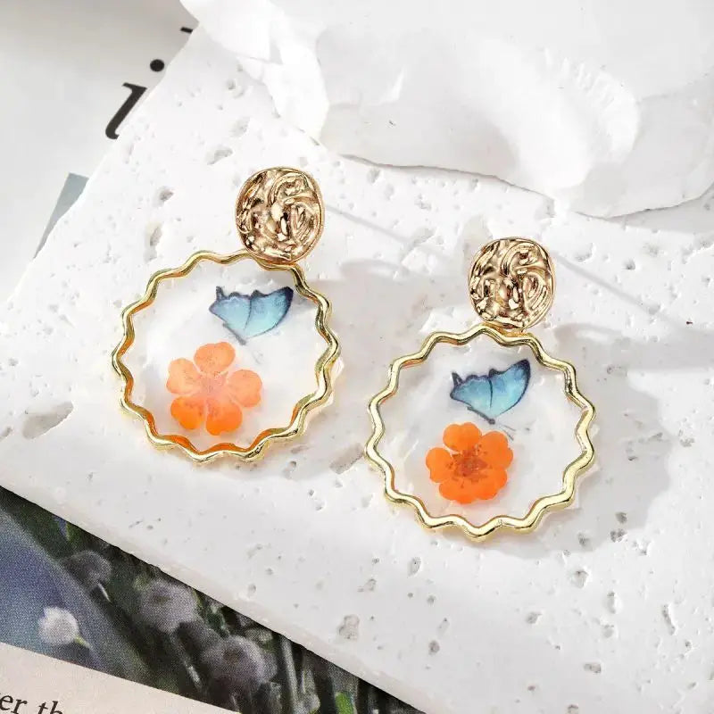 Simples Market natural flower dangle earrings, gold-tone wavy hoop with pressed orange flower and blue leaf resin pair