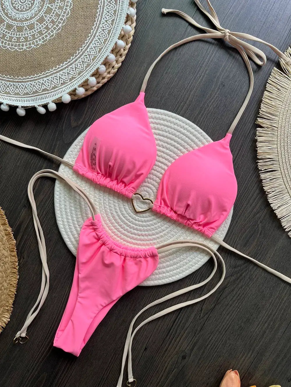 Two-piece hot pink bikini with halter triangle top and thong bottoms, beige straps.
