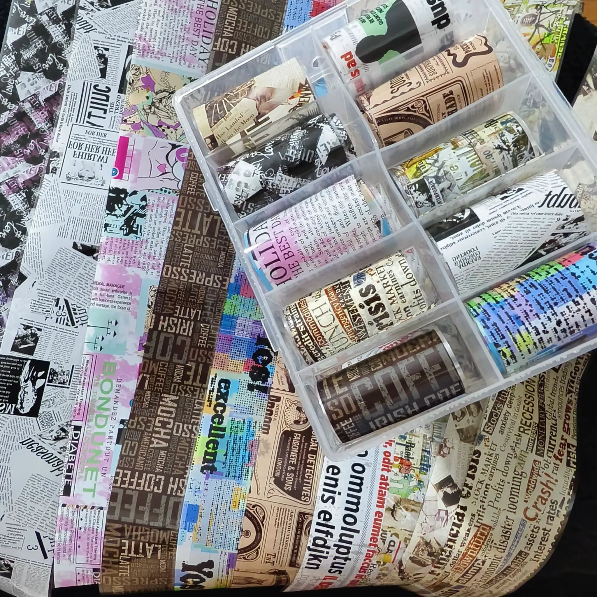Nail foil transfer papers; 10 rolls with newspaper print designs in a clear plastic organizer