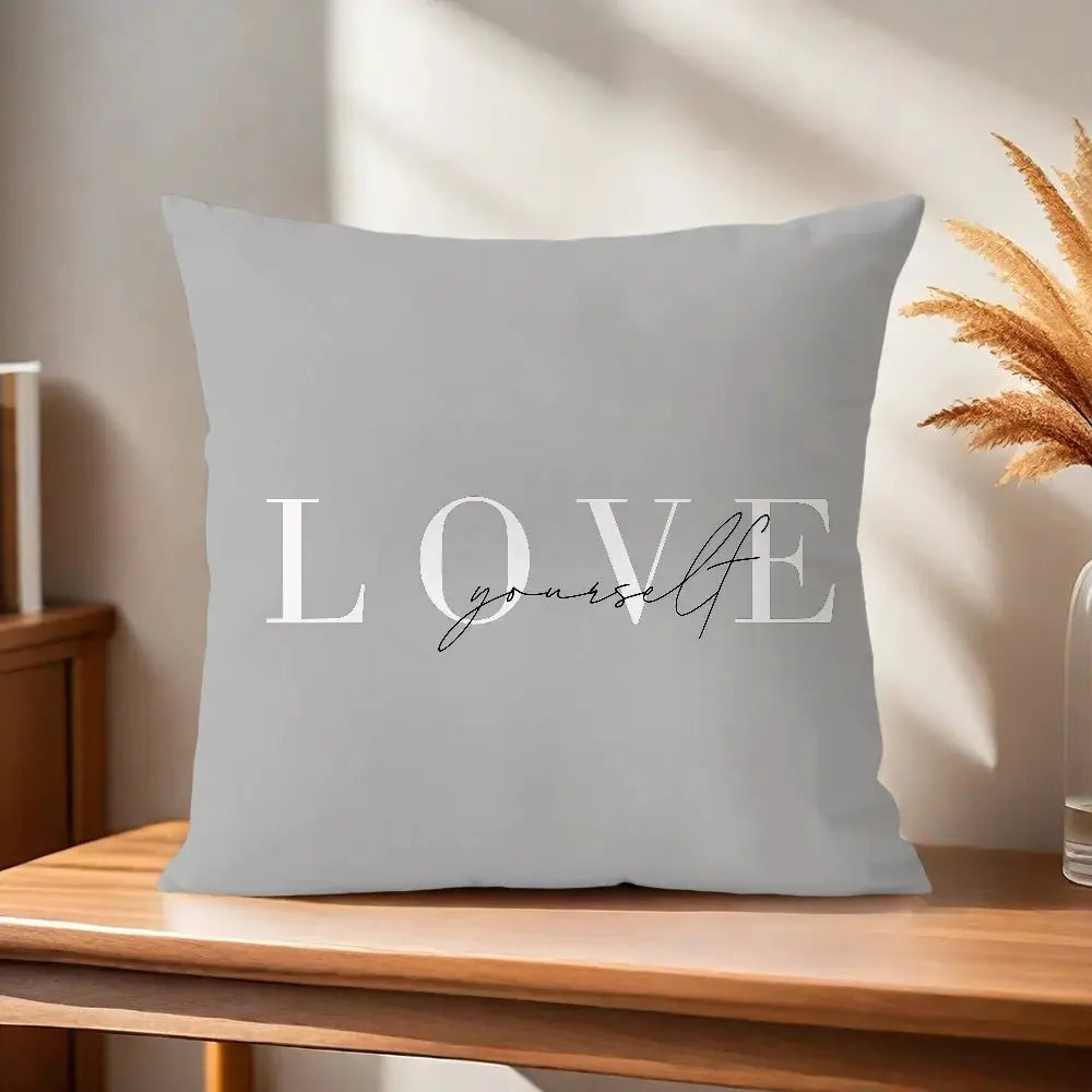 Gray pillow cover with white LOVE Yourself typography decorative cushion on a wooden table