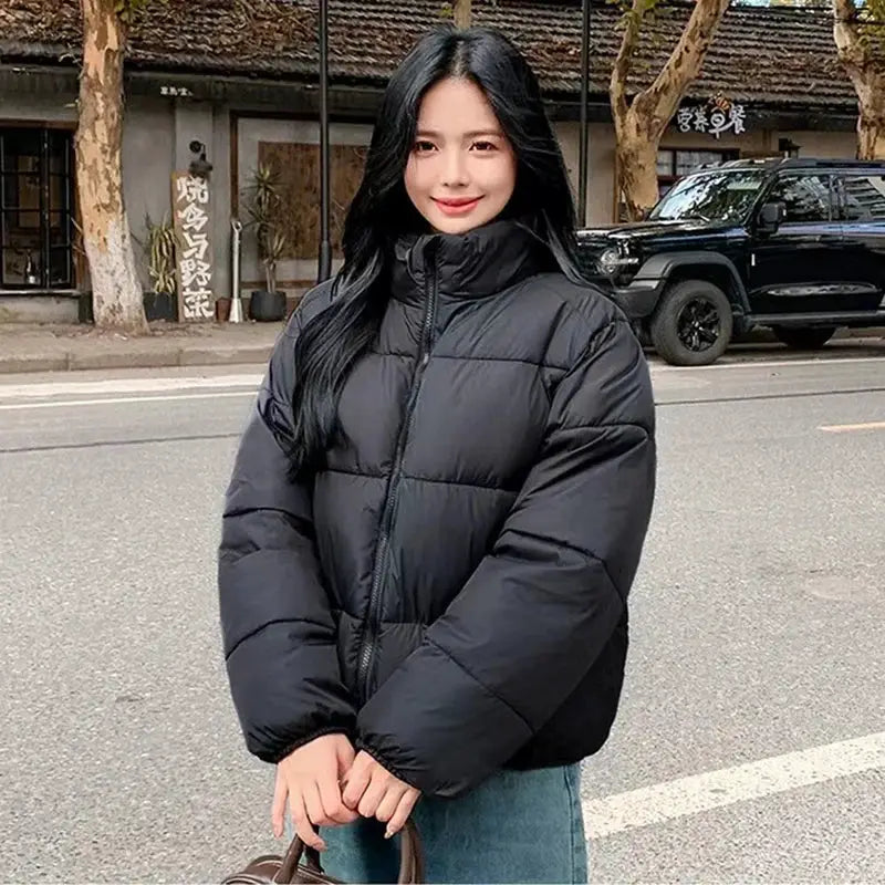 Black puffer jacket worn by a woman on a city street, casual streetwear look