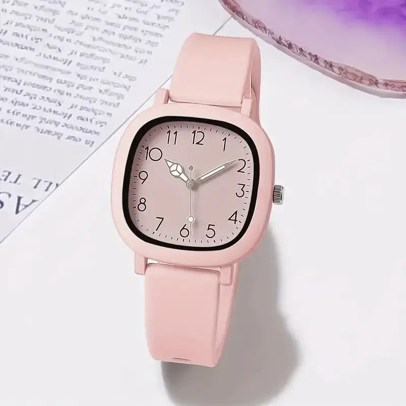 Watch with pink silicone band, square case, light pink dial and Arabic numerals.