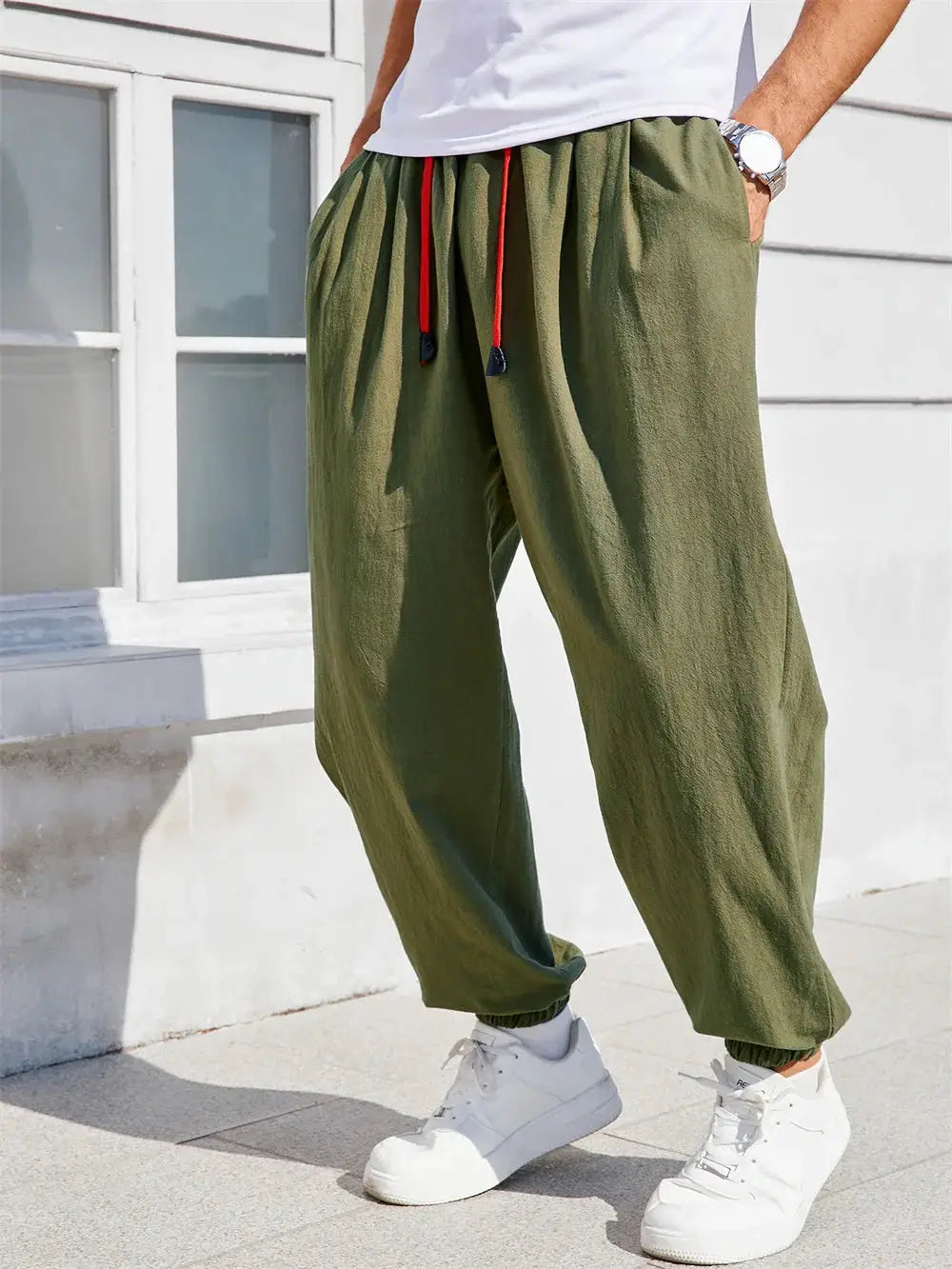 Men's olive green cotton-linen harem pants, loose-fit casual joggers with red drawstrings.