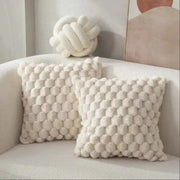 2 cream turtle-pattern plush throw pillows with chunky bubble texture on a sofa