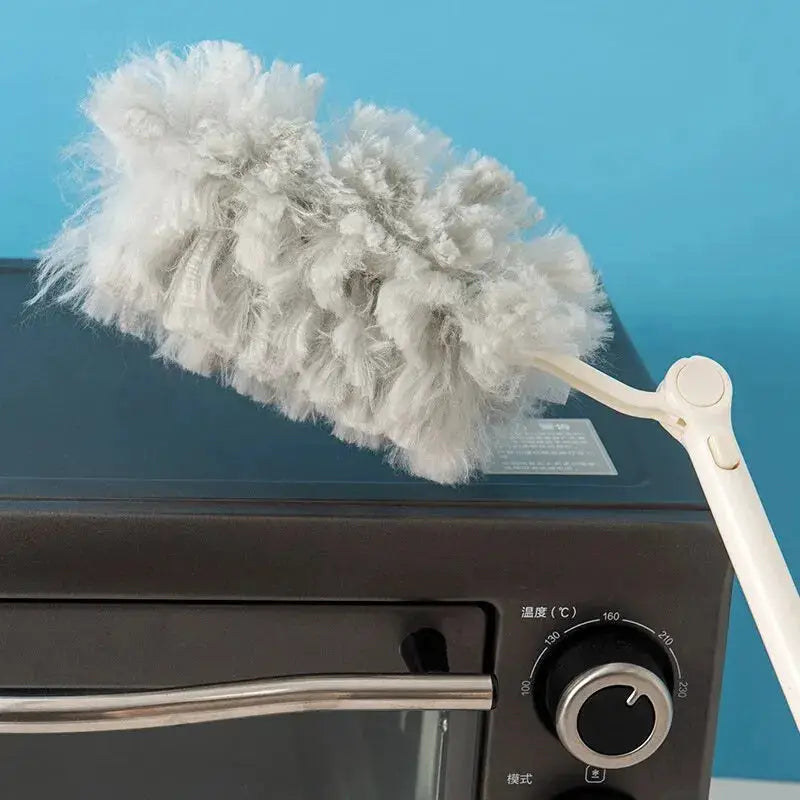 Extended-pole dust collector with white microfiber head on a long handle resting on a microwave oven.