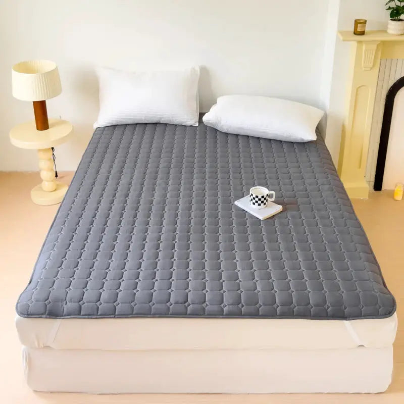 Waterproof quilted mattress protector cover in gray on a bed with two white pillows