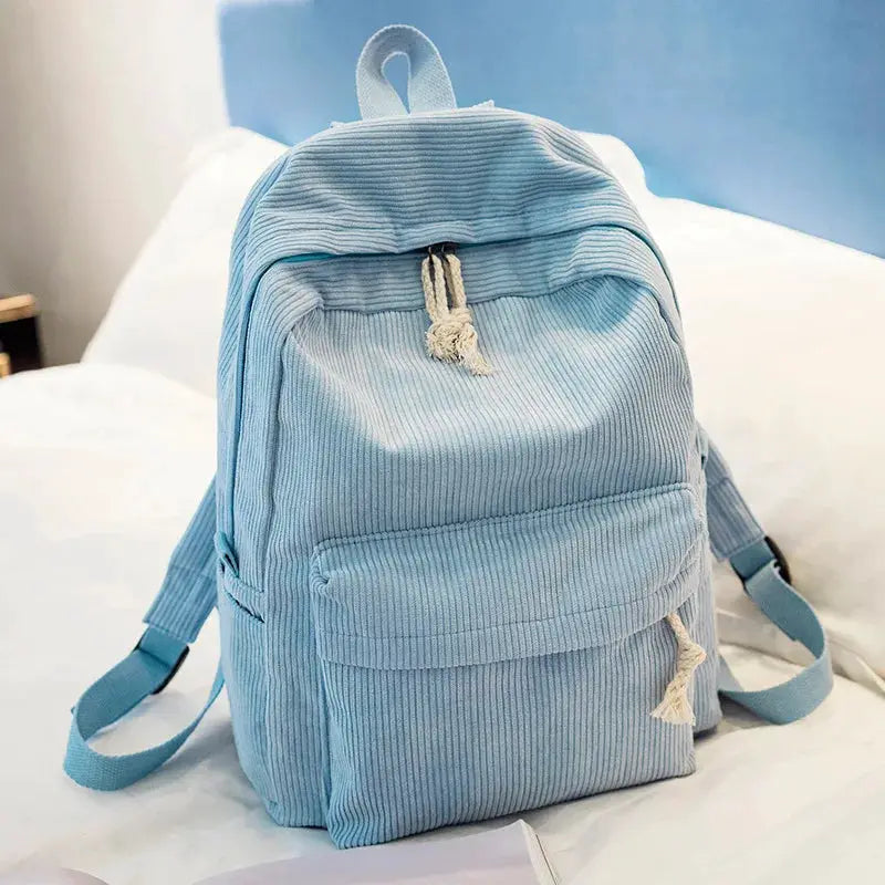Personalized kids backpack by Simples Market in light blue corduroy with front pocket and drawstring tassels.