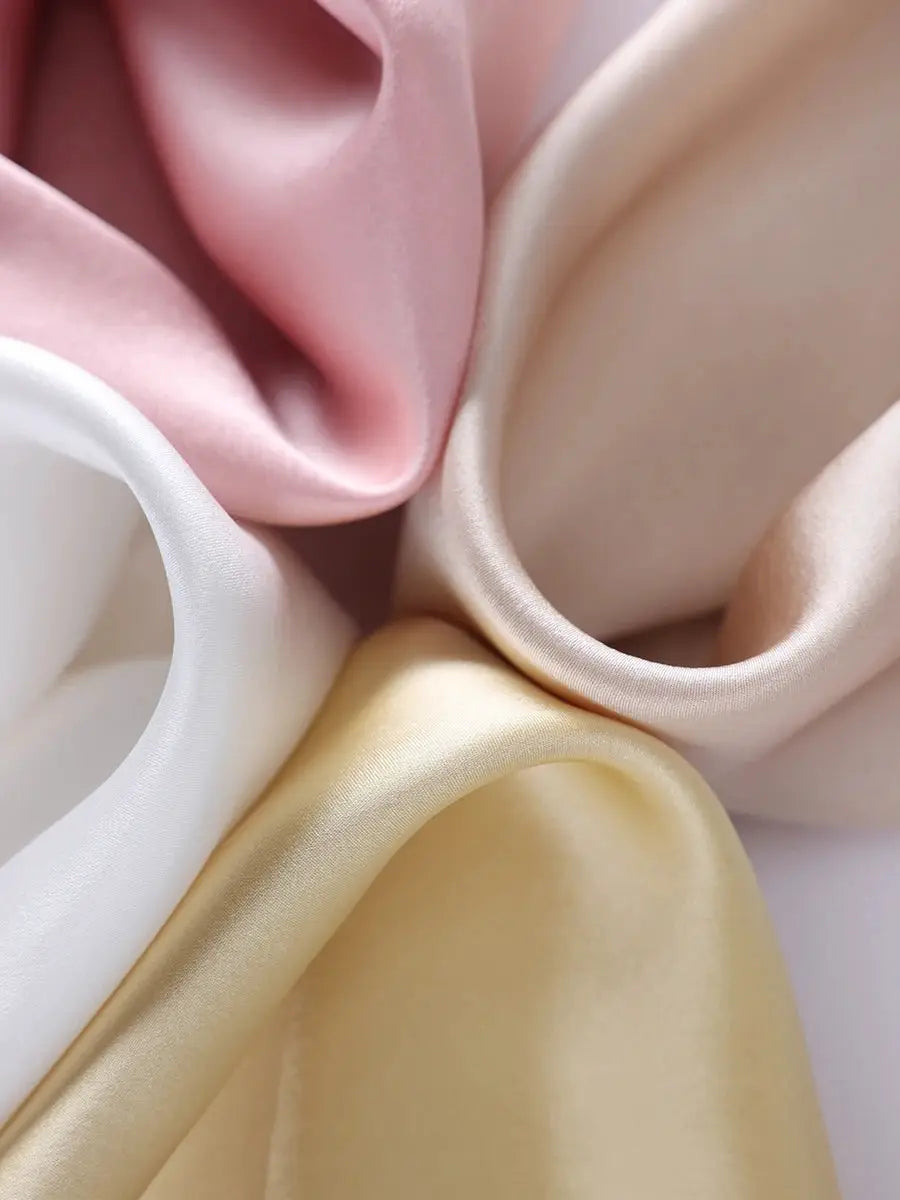 Silk fabric swatches in pastel pink, white, ivory and beige; smooth satin texture