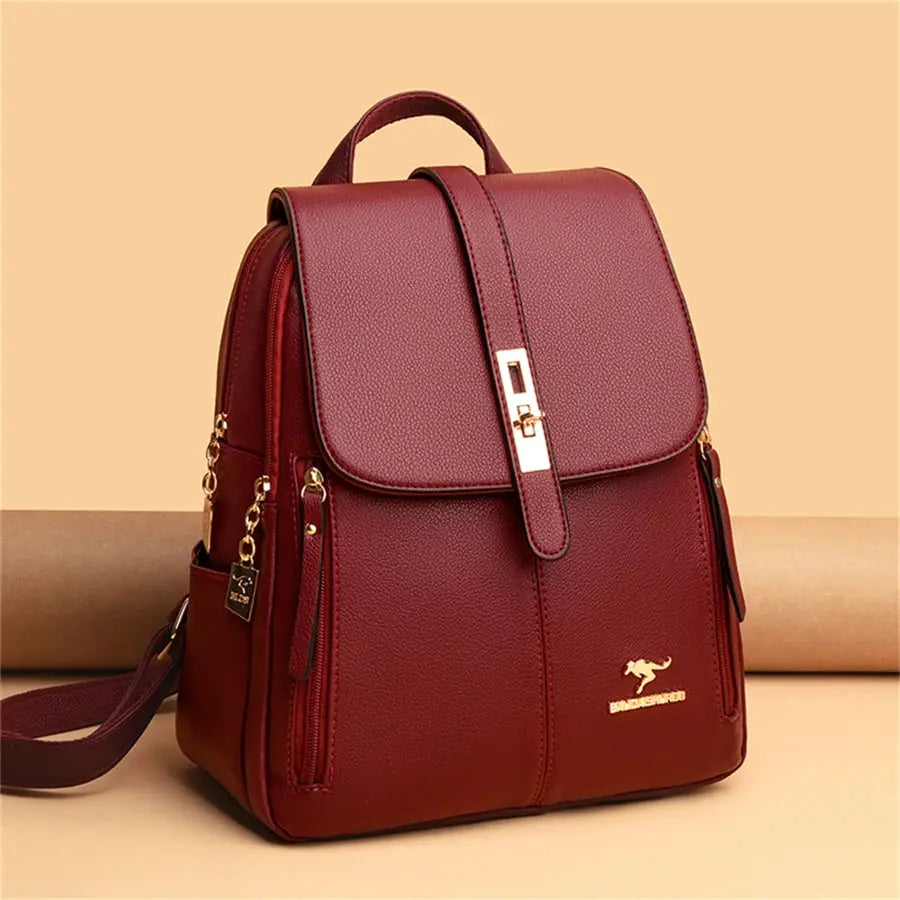Leather backpack in burgundy with gold hardware, top handle, side zips and Burberry-style logo plaque.