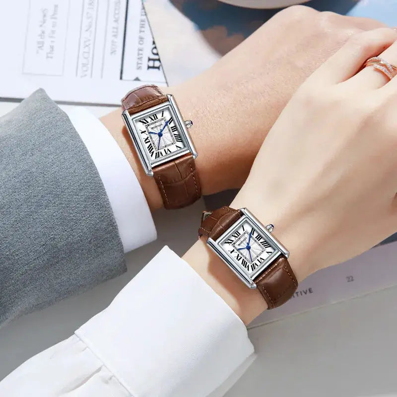 Two matching couple's watches with brown leather straps, rectangular silver cases, and Roman numeral dials.