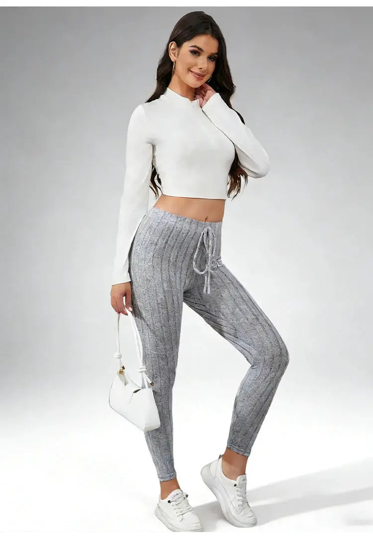 Women's gray knit joggers with elastic drawstring waist, ankle-length, paired with white cropped top and sneakers