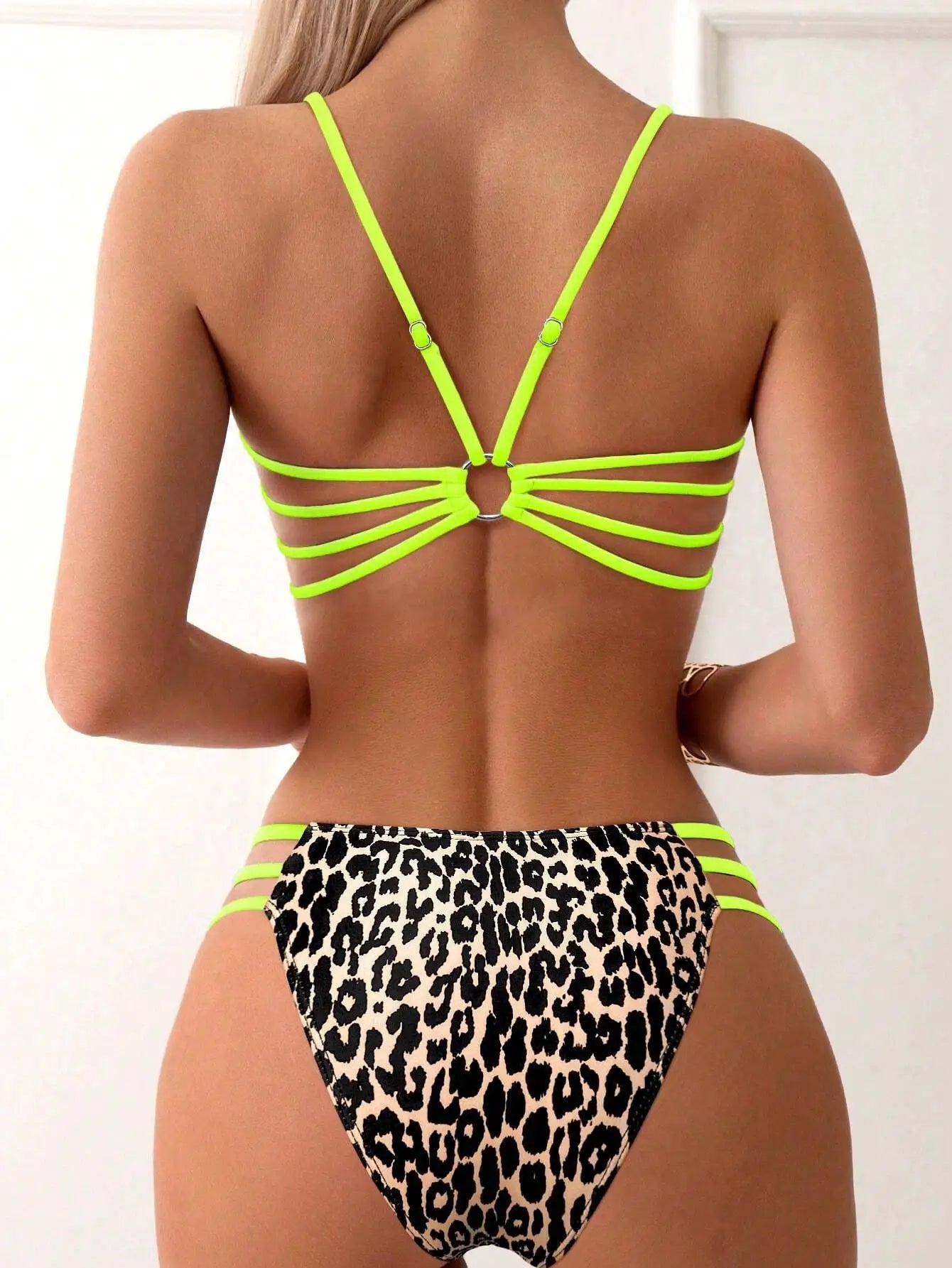 Strappy neon-green bikini set with leopard-print bottoms; back view shows multiple side straps and a ring detail.