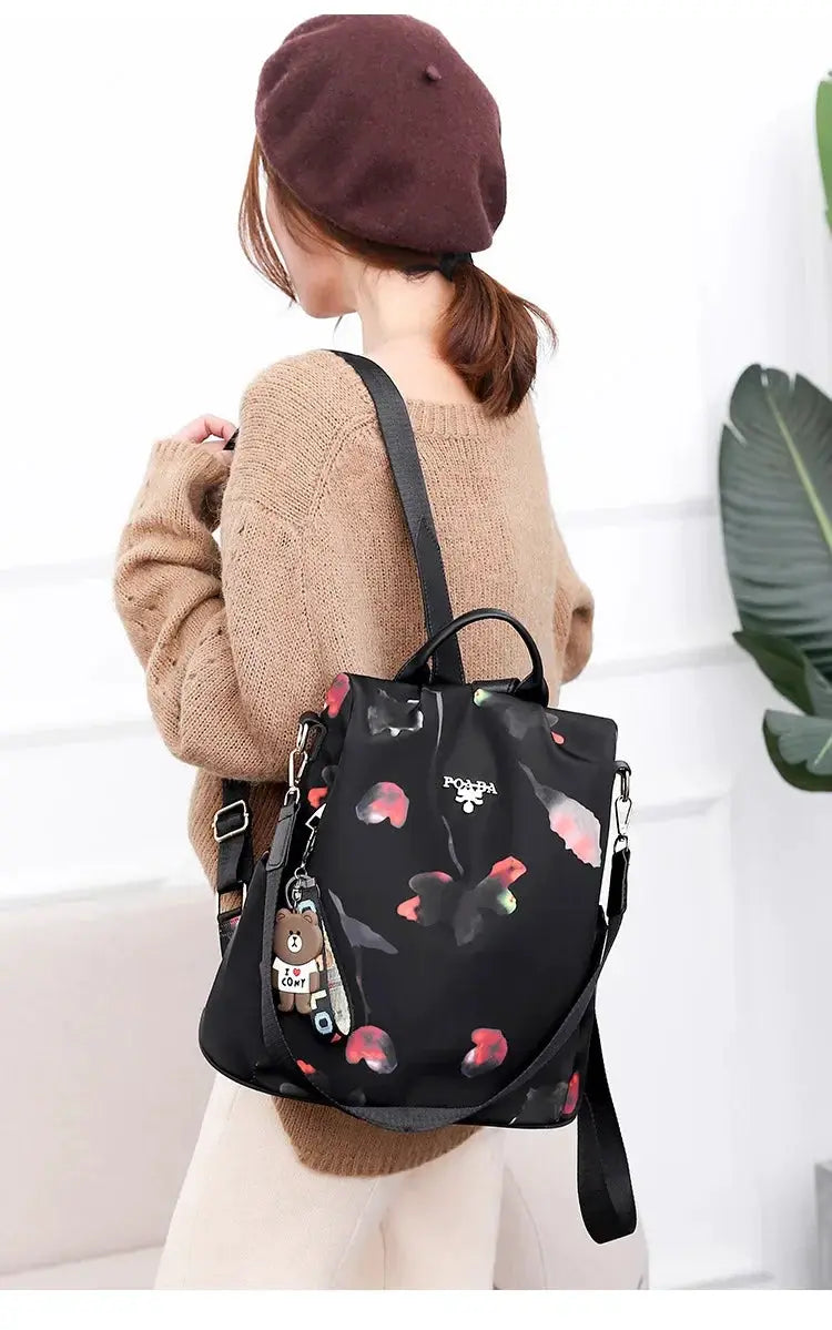 Women's backpack Simples Market black floral Oxford cloth bag with top handle, adjustable strap, and bear keychain