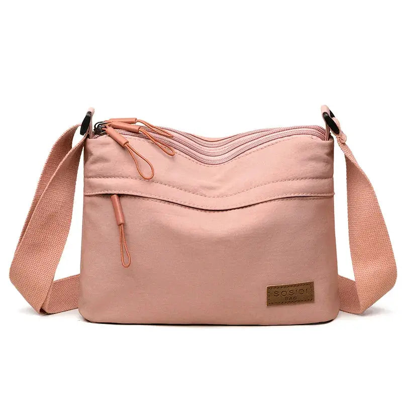 Pink canvas crossbody bag with front zip pocket and adjustable strap