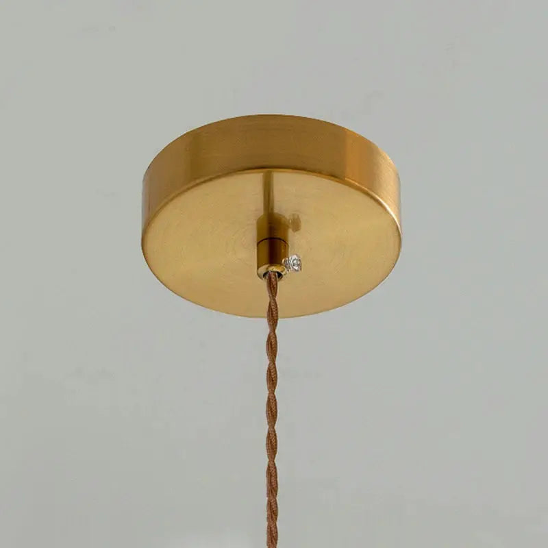 Brass round ceiling light fixture with a twisted brown fabric cord, vintage style.