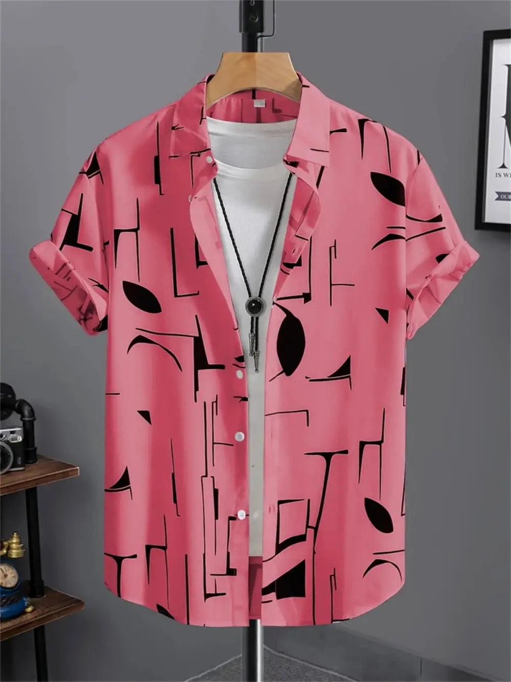 Pink short-sleeve shirt with black abstract geometric print, layered over white tee on display.
