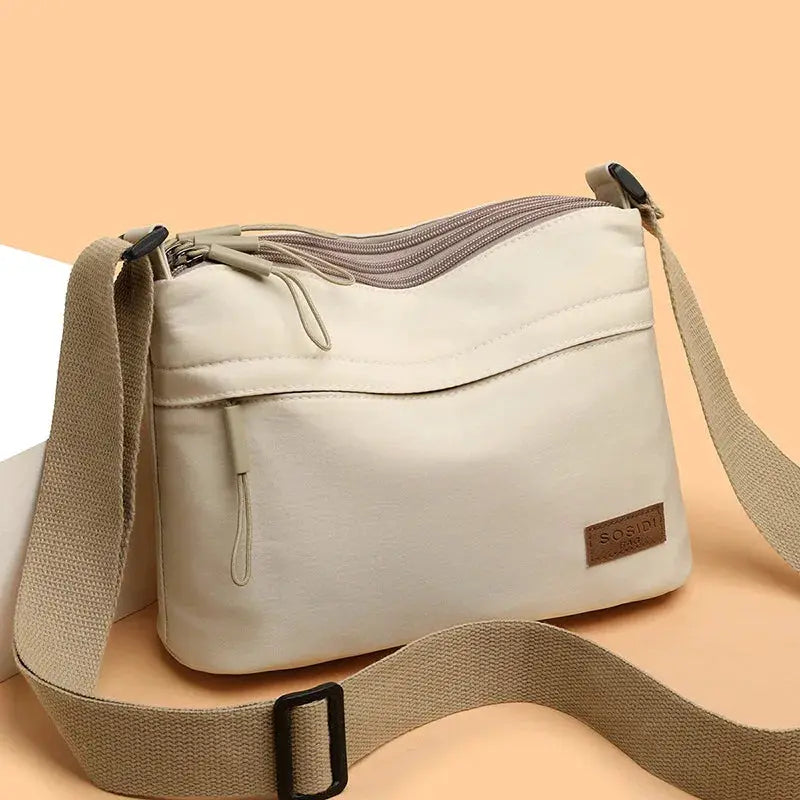 Beige canvas shoulder crossbody bag with 3 main pockets and adjustable wide strap