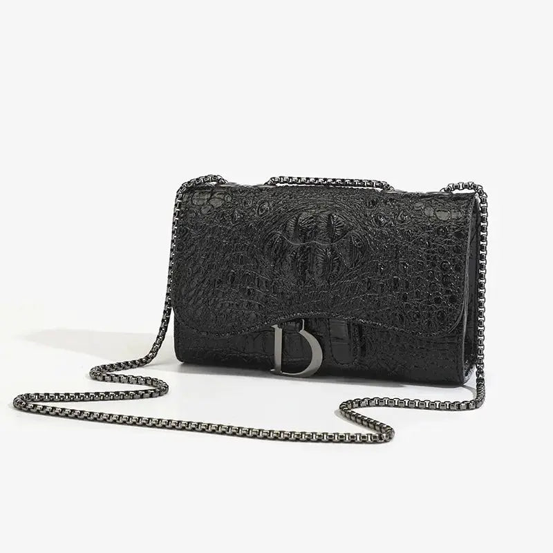 Women's luxury crossbody handbag in black crocodile-embossed leather with a silver chain strap and metallic D clasp.