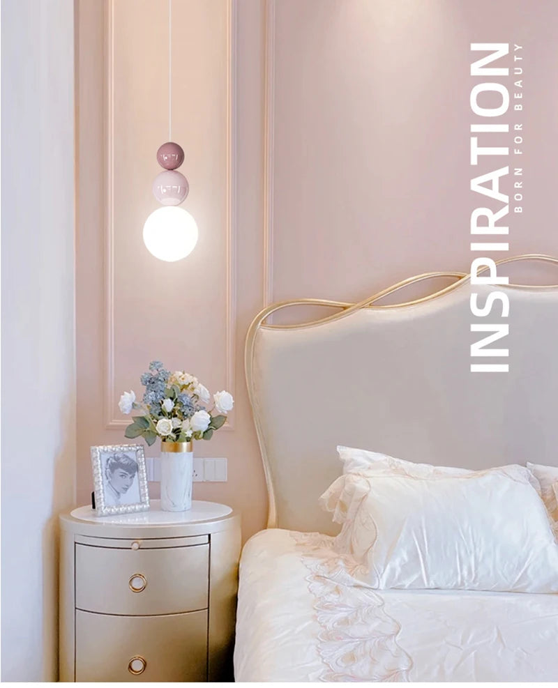 Nordic pendant light with stacked pink glass orbs and a bright LED bulb, cream bedroom decor.