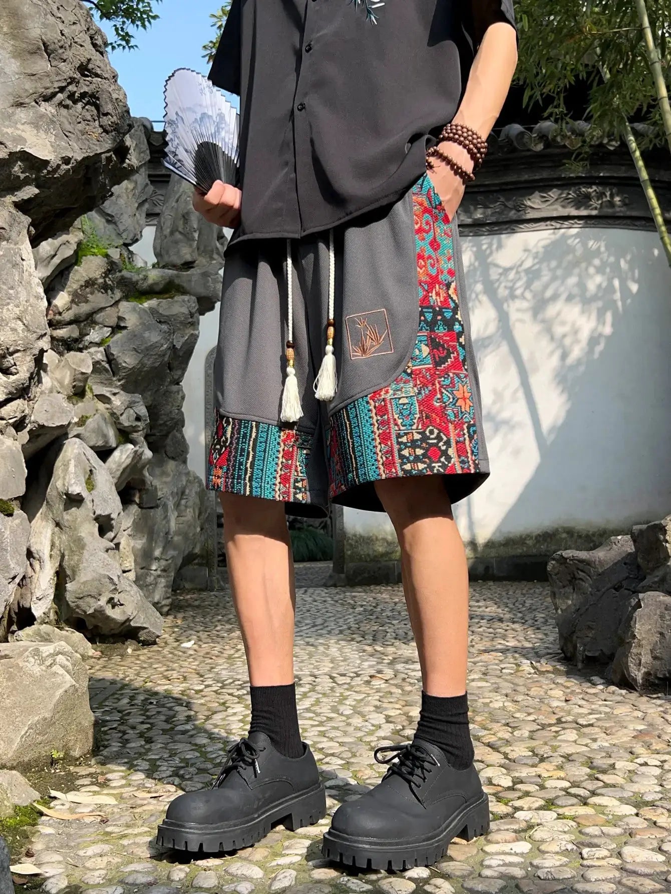 Men's ethnic embroidery shorts with pockets and tassel drawstring; gray with colorful side-panel pattern.
