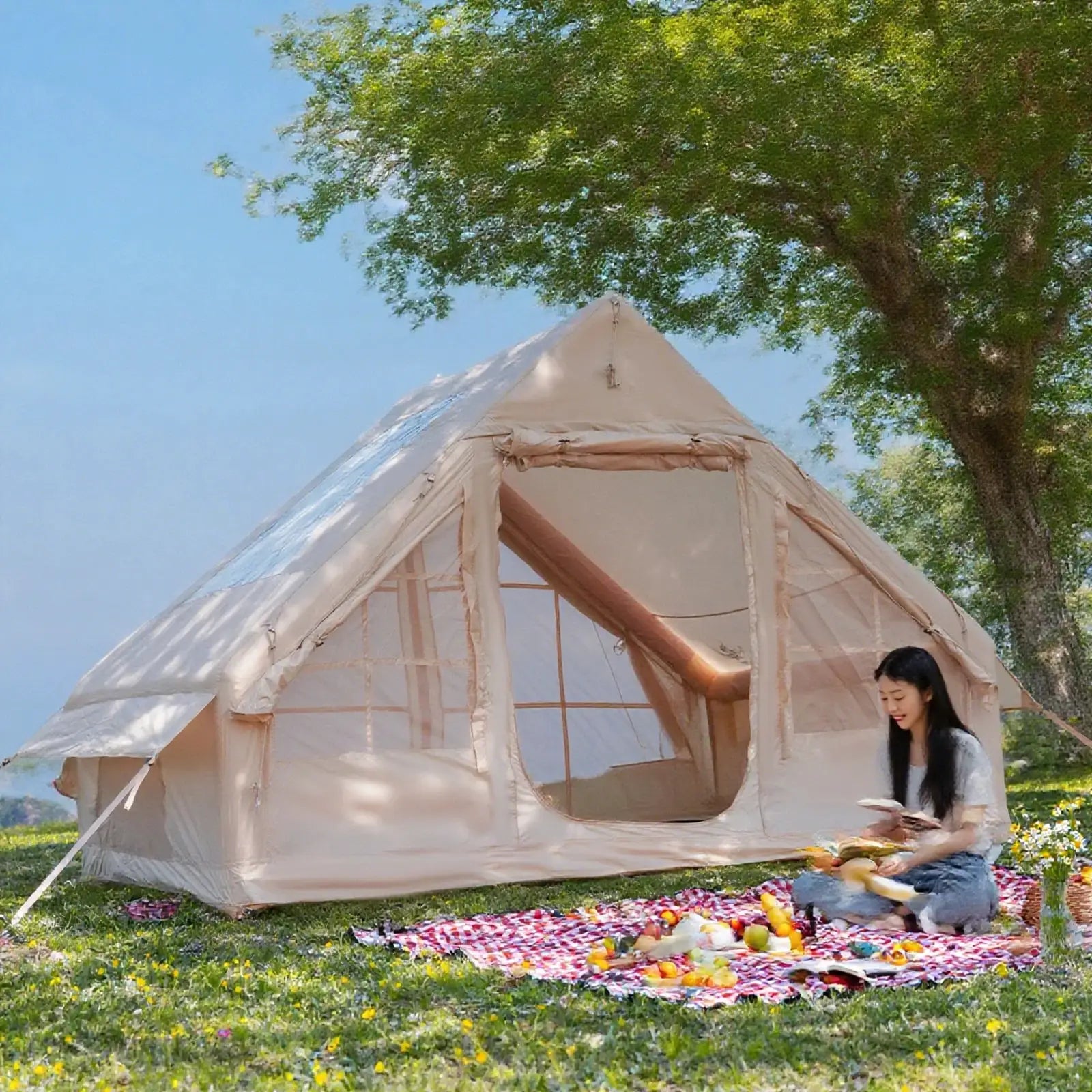 Beige inflatable family camping tent with open front entrance on grassy campsite under a tree