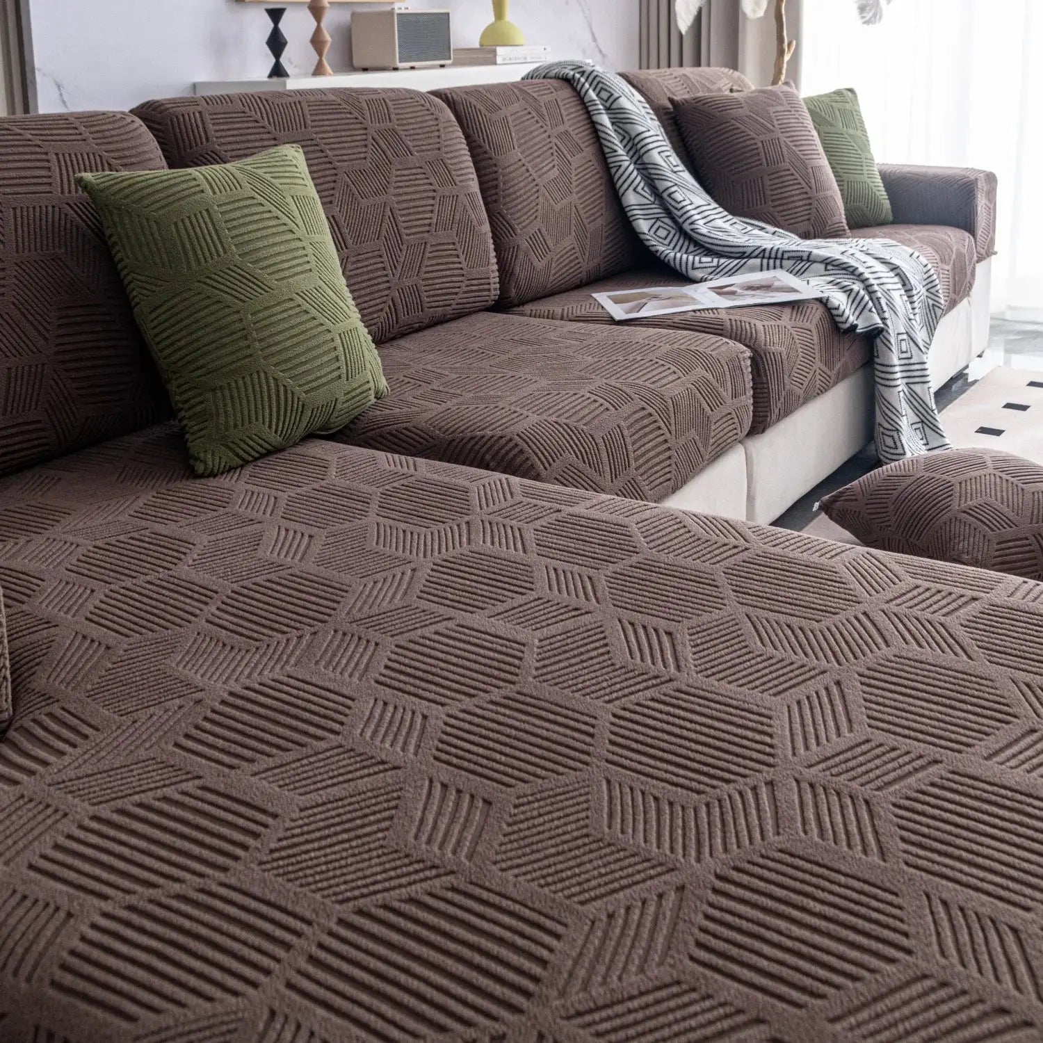 Sofa cover in brown jacquard stretch with two green cushions on a living room sofa