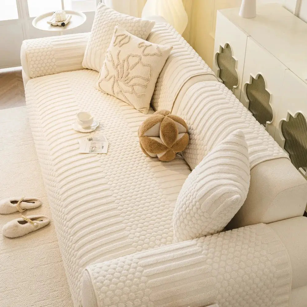 Thick geometric jacquard fleece anti-slip sofa cover in cream on a couch with matching cushions