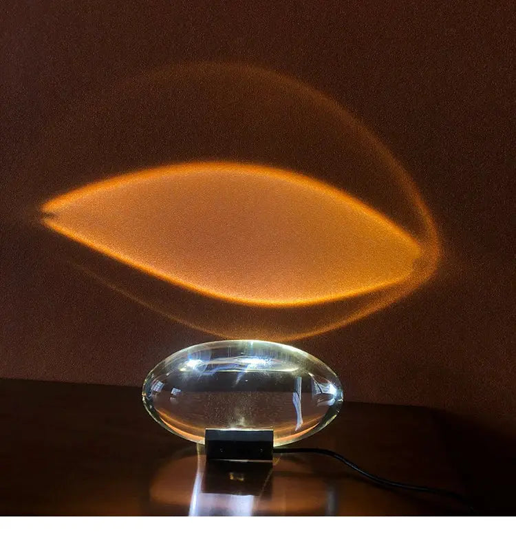 Egg-shaped LED crystal table lamp with black base projecting warm amber light