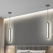 Two black oval minimalist LED pendant lights hanging from ceiling in a bedroom.