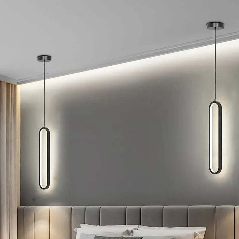 Two black oval minimalist LED pendant lights hanging from ceiling in a bedroom.