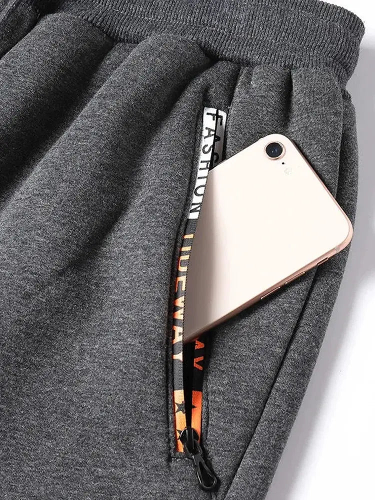 Men's grey fleece sweatpants with a zip side pocket holding a smartphone.