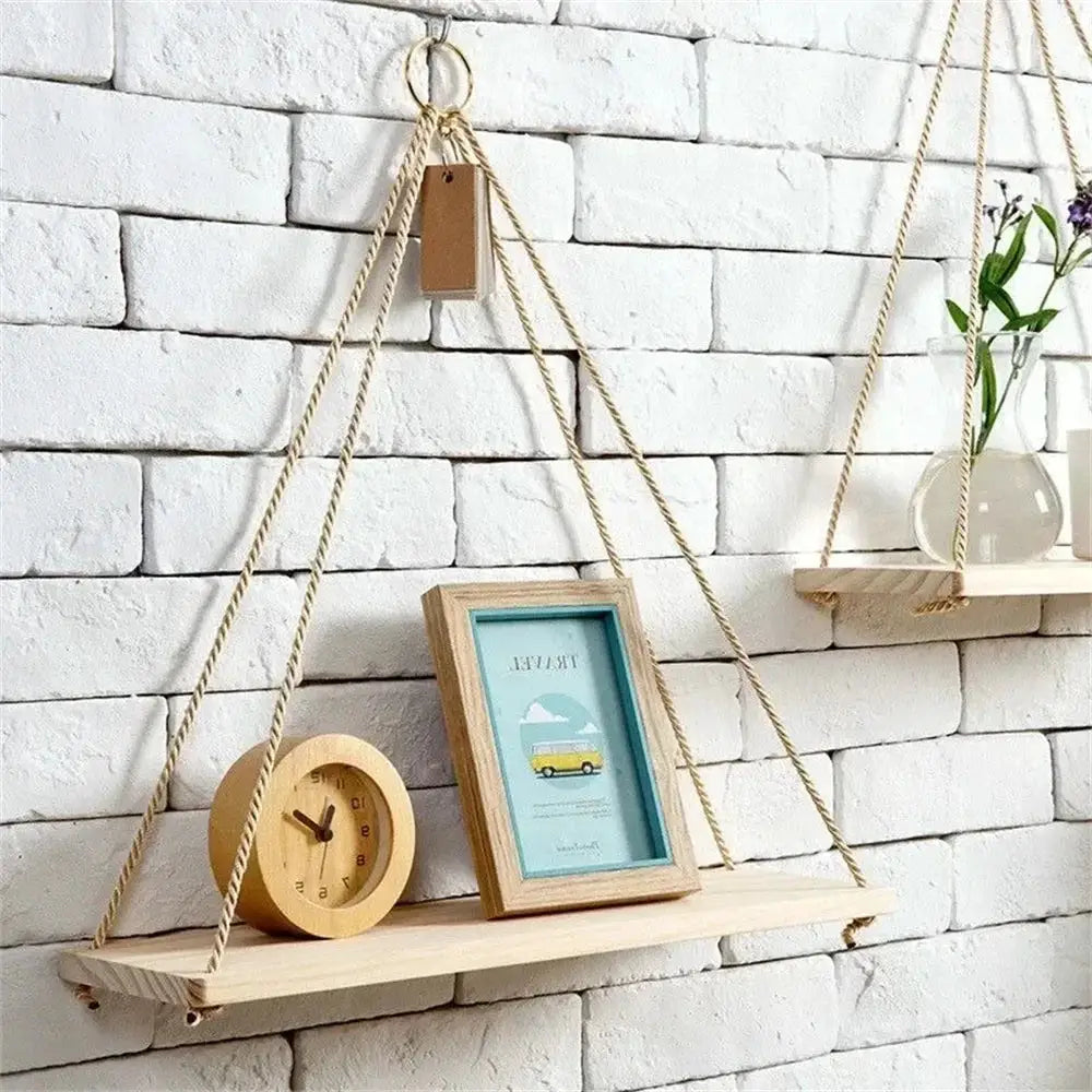 Wood hanging shelf with hemp rope, mounted on white brick wall, displaying a clock and turquoise-framed print.
